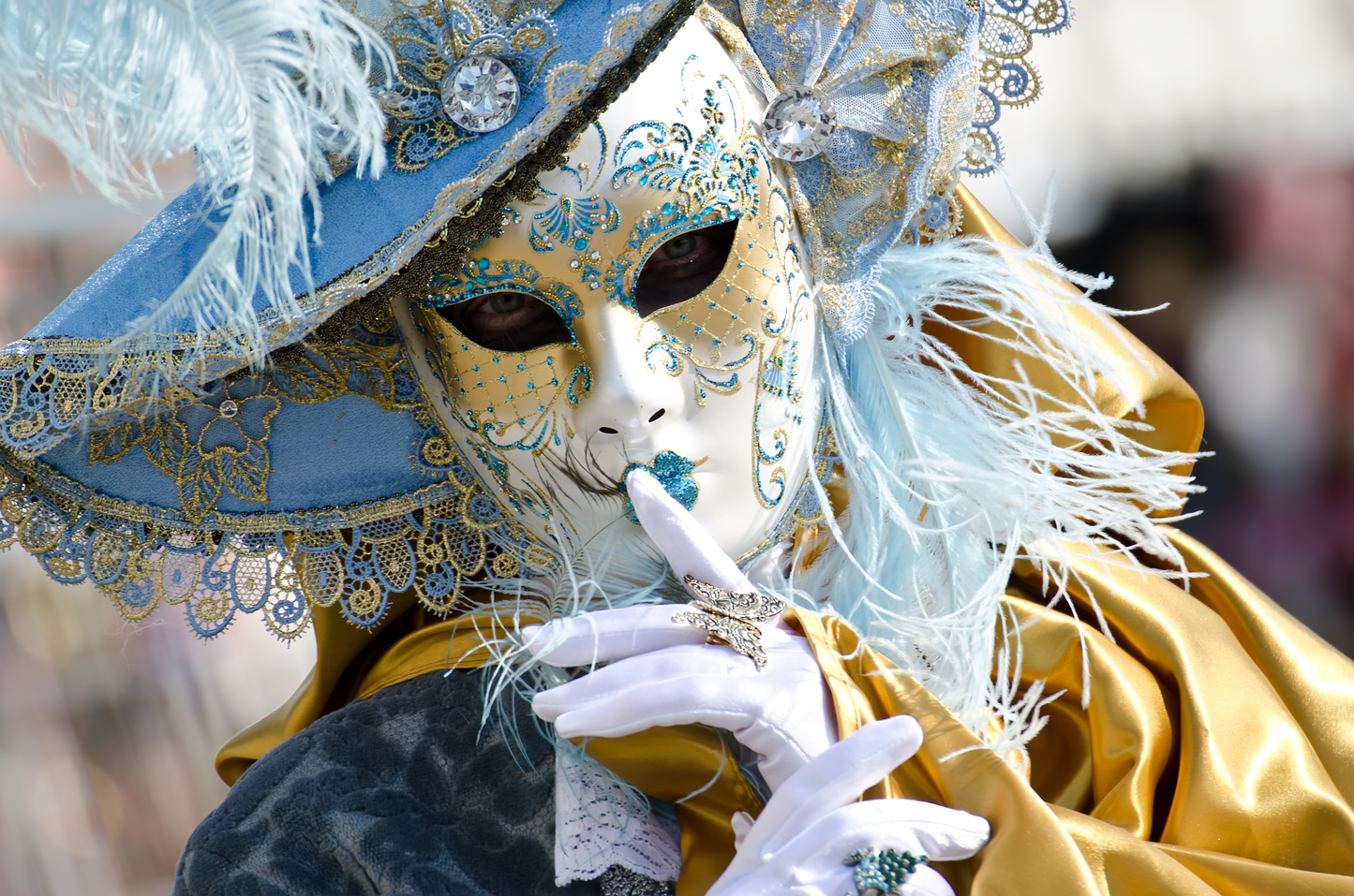 Porträt einer Person mit venezianischer Maske in Blau, Weiß und Gold mit Federn und Handschuhen