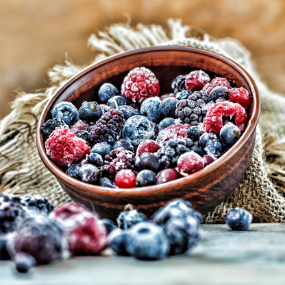 Schale mit gefrorenen Himbeeren, Brombeeren, Heidelbeeren und Johannisbeeren auf rustikalem Stoff