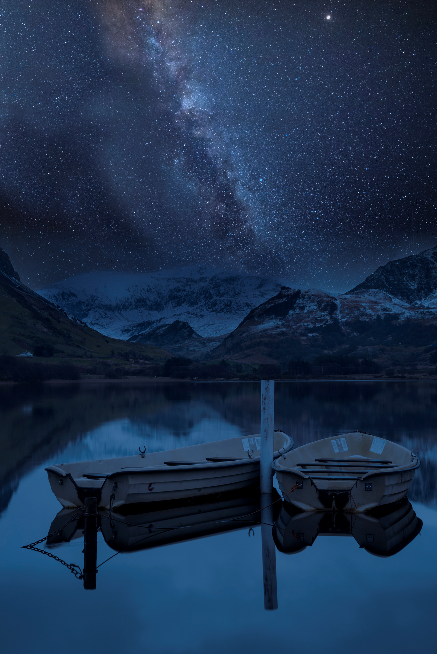 Zwei Boote auf stillem Bergsee bei Nacht unter der Milchstraße und sternenklarem Himmel