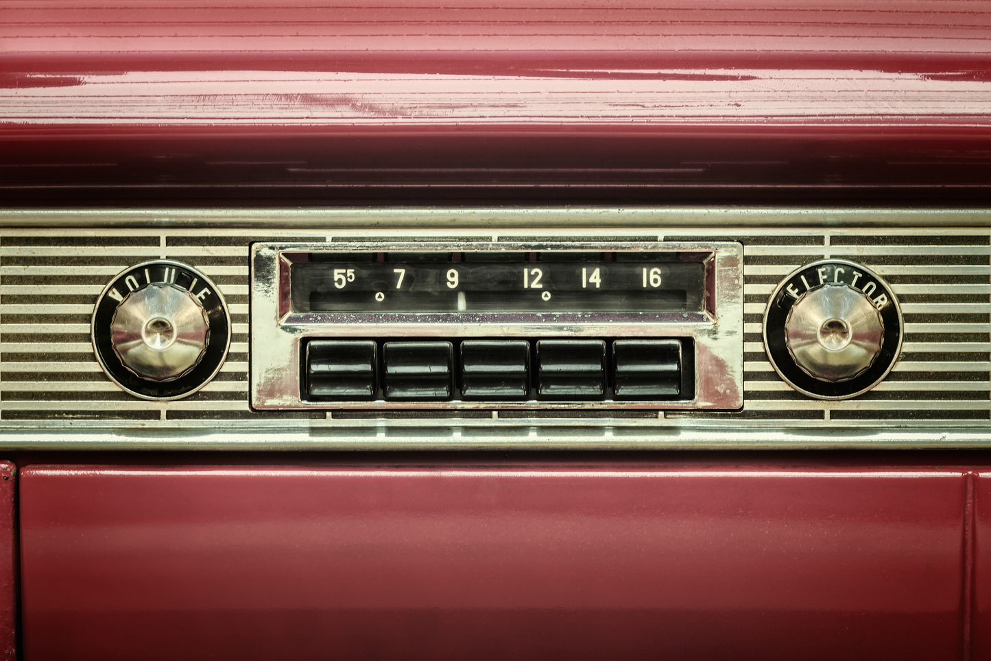 Detailansicht eines klassischen Autoradios mit Knöpfen und Frequenzanzeige in rotem Vintage-Interieur
