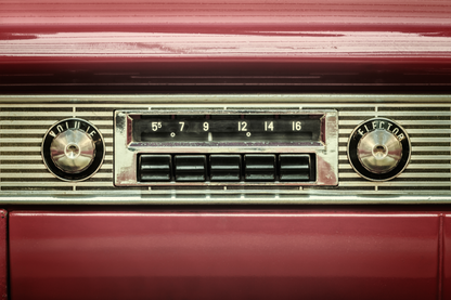 Detailansicht eines klassischen Autoradios mit Knöpfen und Frequenzanzeige in rotem Vintage-Interieur