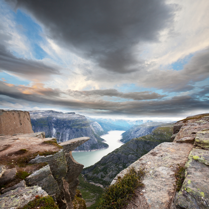 Felsige Aussicht über einen nordischen Fjord mit hohen Bergwänden, hellem Wasserlauf und dramatischem Wolkenhimmel als modernes Landschafts-Wandbild.